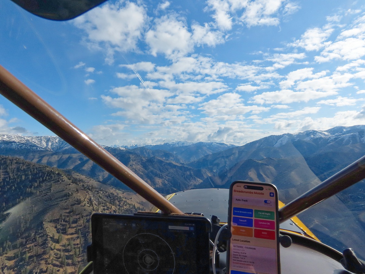 Breadcrumbs Mobile running on an iPhone mounted in a backcountry aircraft cockpit, snowy mountains ahead